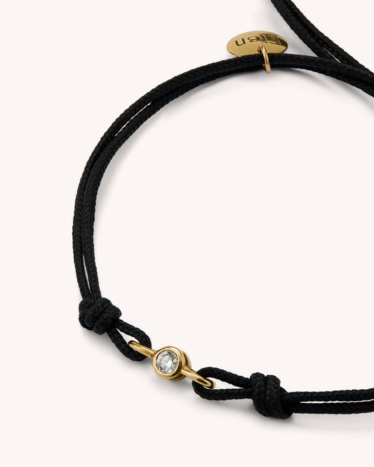 Close-up of EIEN bracelet showing the lab-grown diamond bezel set in gold vermeil with double black cord detail.