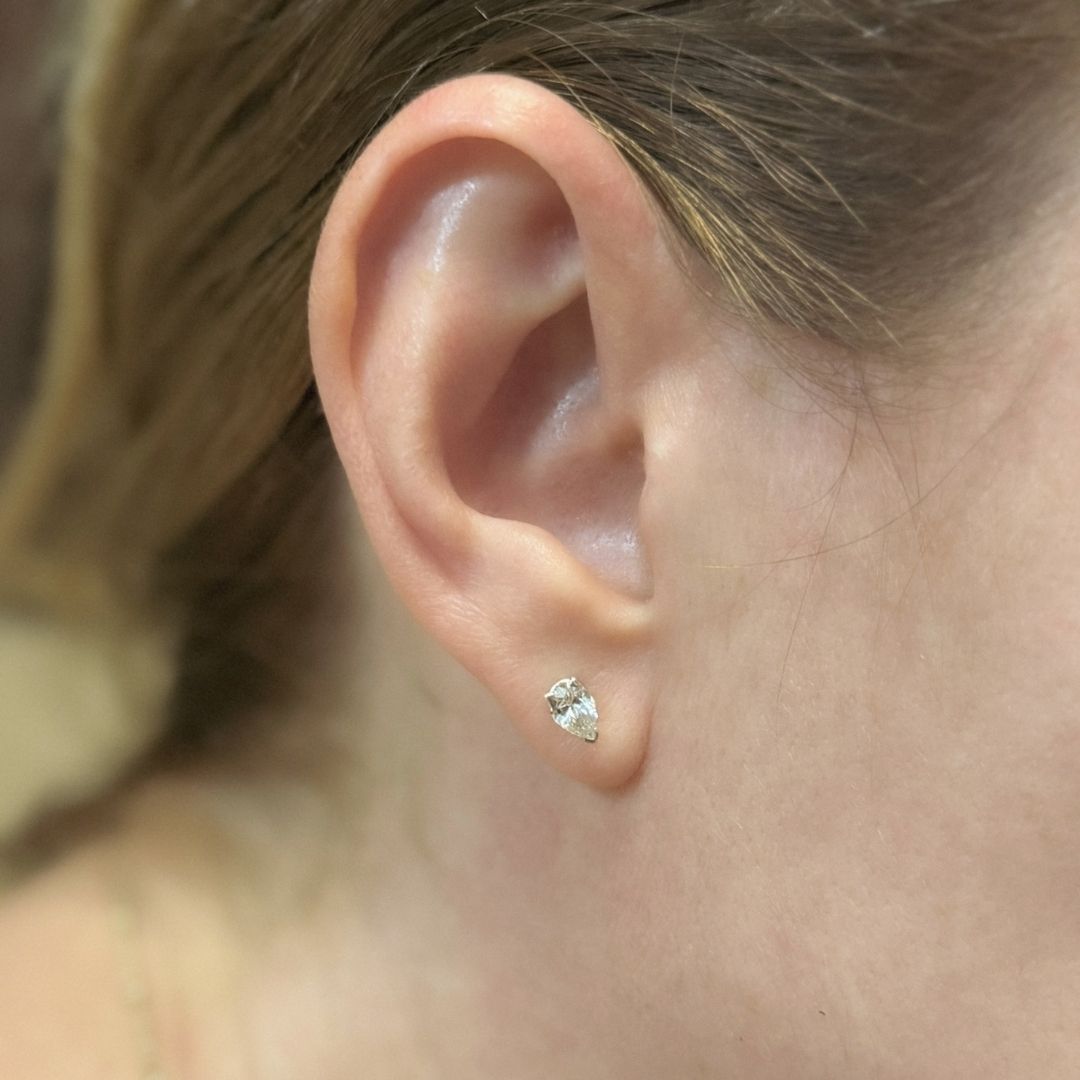 Pendiente de plata con diamante talla pera, puesto en el lóbulo.