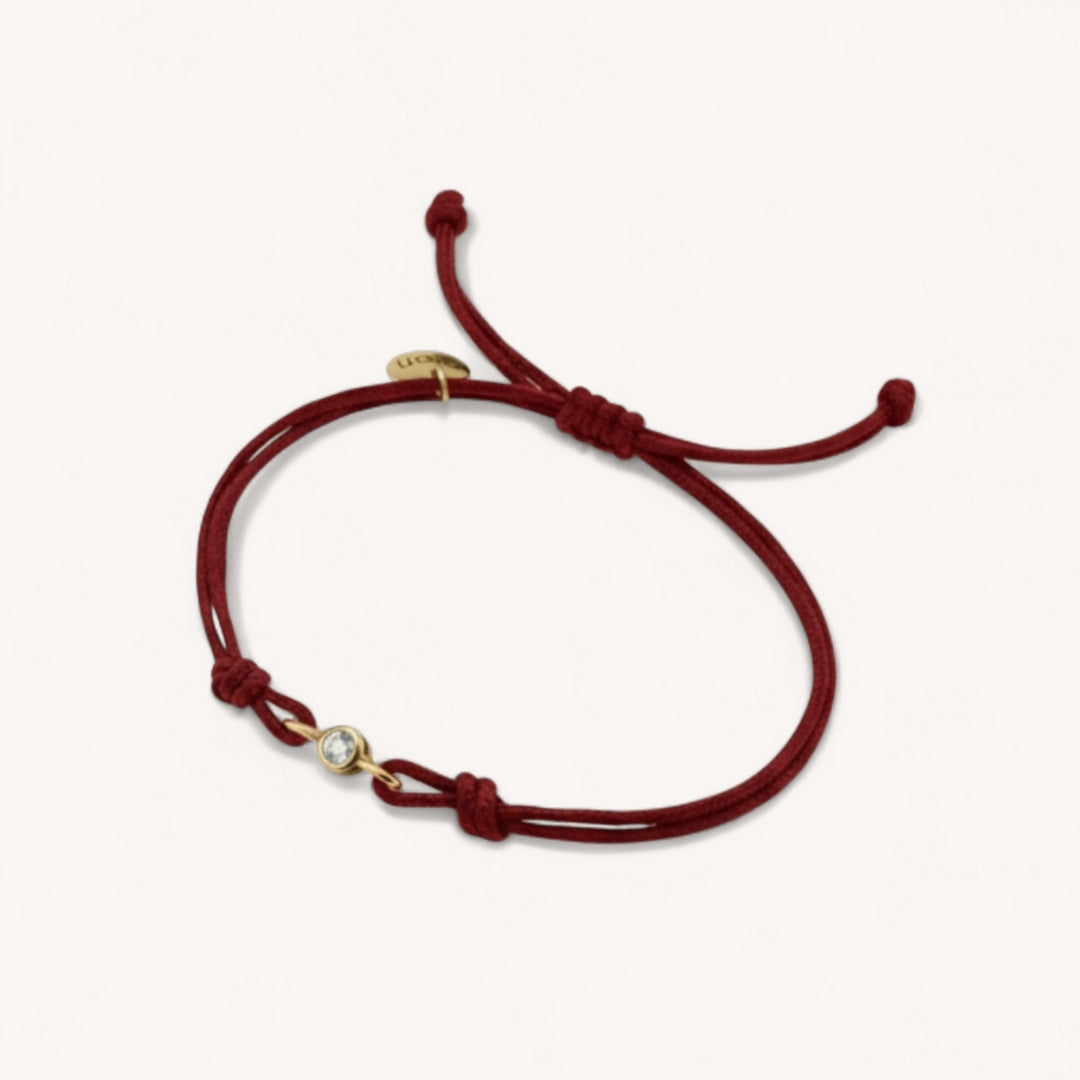  bracelet showing the lab-grown diamond bezel set in gold
vermeil with double burgundy cord detail.